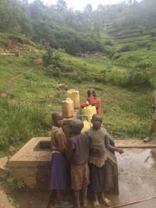 Children collect water from a tap stand in the mountains that is fed by gravity from a nearby spring